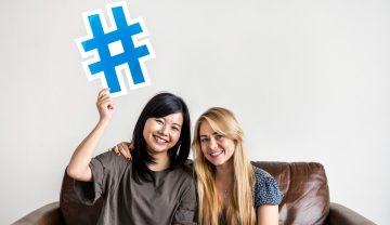 Featured image of the article showing two women holding a hashtag above their heads